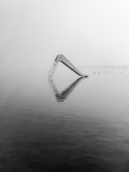 A white slide in the middle of water on a misty morning. Kralingse Plas, Rotterdam.